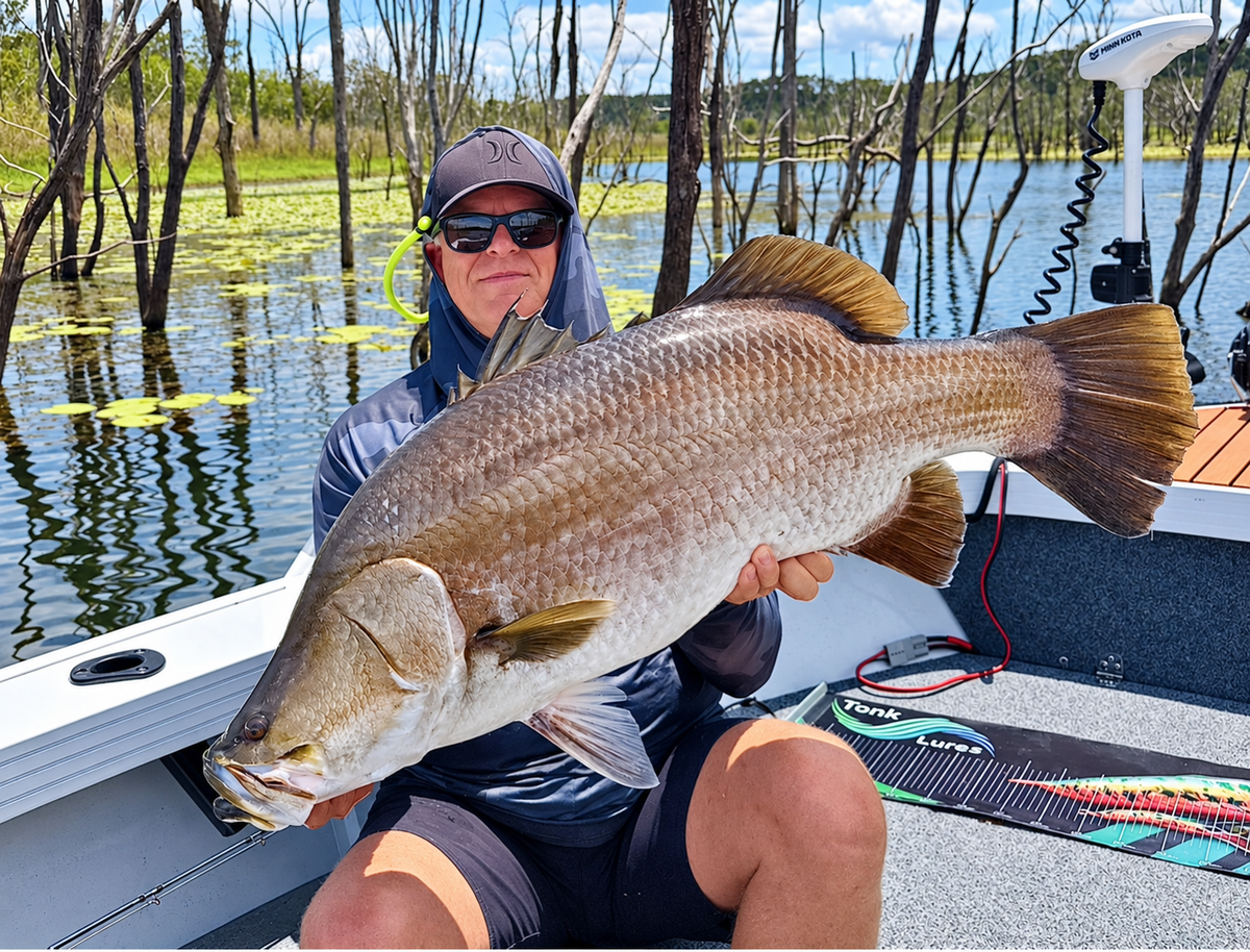 Angler holding a large barramundi aboard a fishing boat